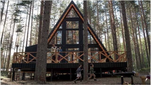 A-frame дом с треугольной крышей среди сосен